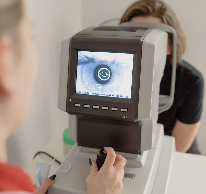 Unrecognizable ophthalmologist checking eyesight of woman on vision screener